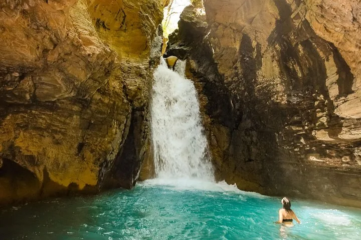 Person, die im türkisfarbenen Becken am Fuß des La-Leona-Wasserfalls schwimmt.