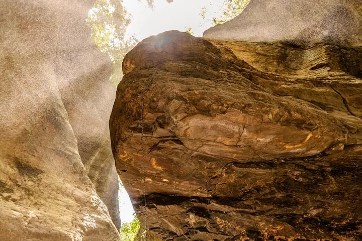 Large textured rock formation inside a canyon with light shining from above.
