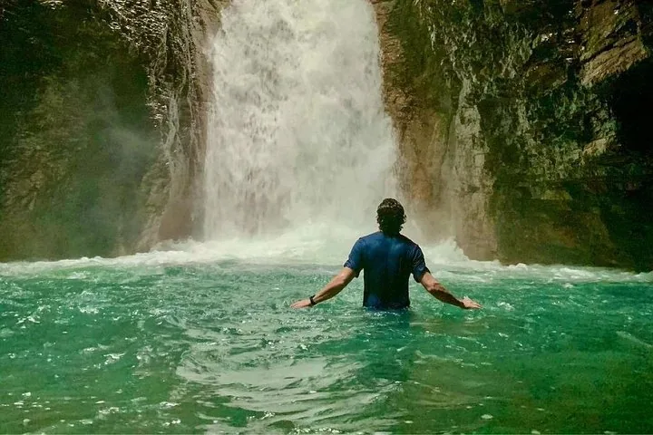 Person, die im Canyon durch das türkisfarbene Wasser zum La-Leona-Wasserfall watet.